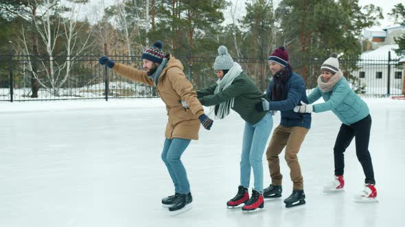 Slow Motion of Joyful Young People Ice-skating in Park Together Laughing Having Fun