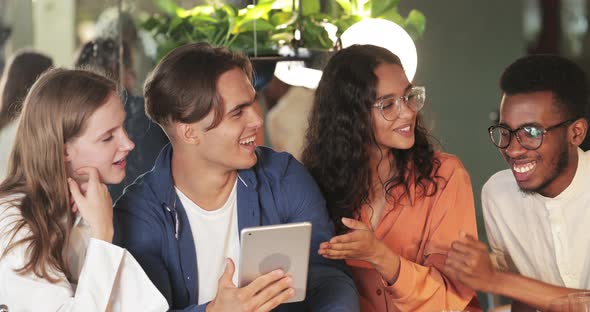 Crop View of Millennial Colleagues Communicating and Smiling. Cheerful Young People Using Tablet