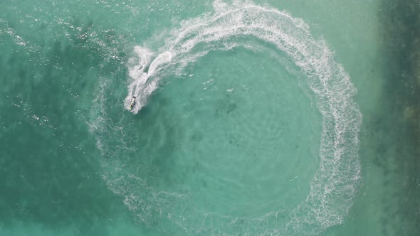 Aerial top view of jet ski or boat drawing a shape on sea ocean turquoise water. Adventure