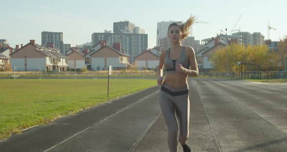 Woman Running at a Stadium in Sunny Day