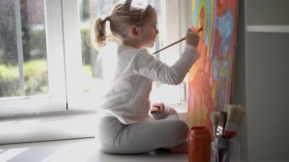 Little girl painting picture with paintbrush