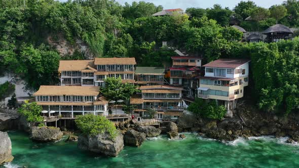 zoom out aerial of tropical waterfront hotel on cliff in Uluwatu bali with turquoise ocean