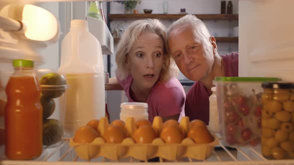 Aged Married Couple Taking Container with Fresh Cherries From Refrigerator