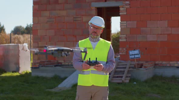 Professional Builder Drone Operator Checks the Work Controls an Aircraft Holding Remote Controller