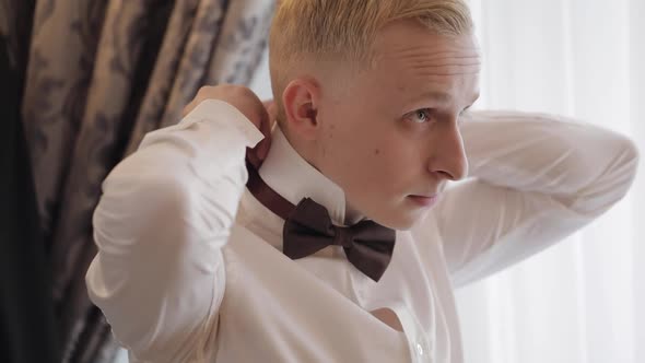 Groom Man Adjusts Bow Tie Preparing to Go to the Bride Businessman in White Shirt Wedding Day