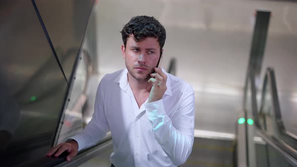 Businessman Speaking on Smartphone on Escalator