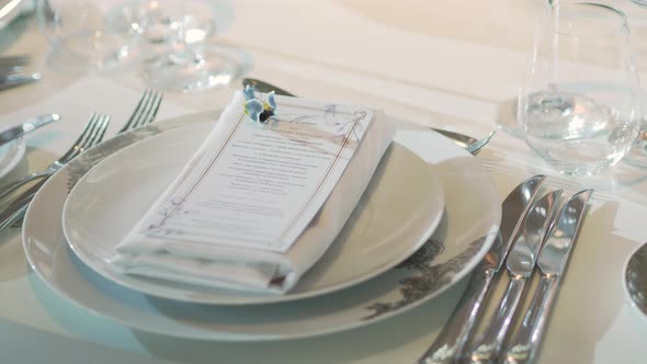 Table Served for Banquet with Cutlery, Wine Glasses and Napkins. Pastel Colored Decorations.