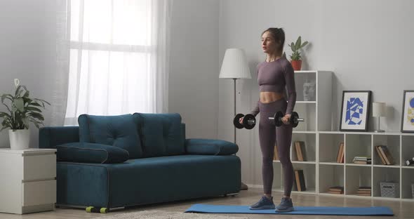 Young Sporty Woman Is Training with Dumbbells Standing in Living Room Portrait of Sportswoman in