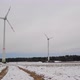 Low angle shot of rotating wind turbines on a snowy field in Germany. Wide shot of a wind farm. - VideoHive Item for Sale