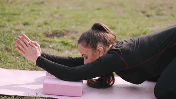 A Sporty Woman Is Doing Stretching on a Mat on the Lawn