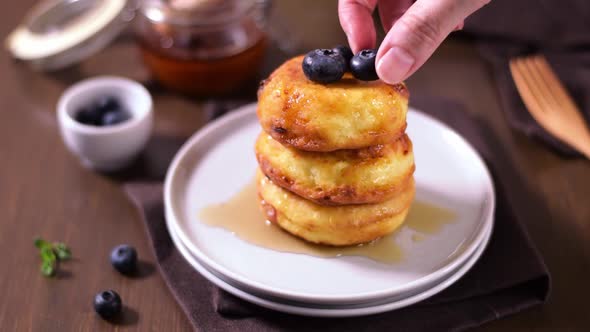 Topping Syrniki, cottage cheese fritters, with blueberry