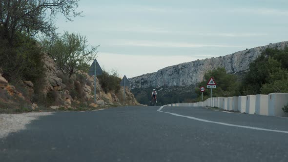 Approaching of Young Pro Female Cyclist on Road