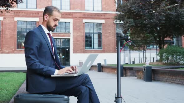 Man in Suit Sitting in Business District Working on the Laptop