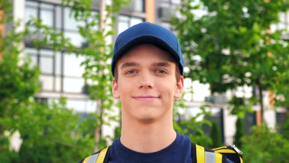 Close Up Smiling Young Man Courier Delivery with Thermal Backpack Looking Camera