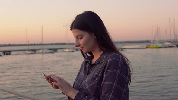 Attractive Woman Using Mobile Phone Outdoor Walking on Pier on Evening Sunset