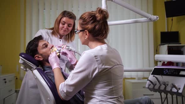 Dentist Cleaning Teeth of Patient in Dental Office