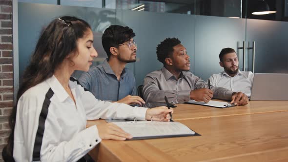 Focused International Employees Sitting in Boardroom Listen Presentation Strategy Training