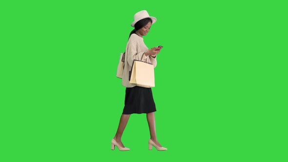 Happy African American Fashion Girl in Knitted Oversized Sweater and Hat Texting on Her Phone