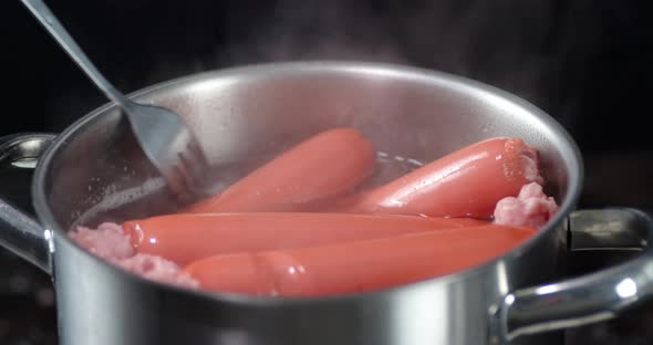 Boiled Sausages in the Pan Stir with a Fork. 