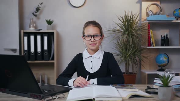 Teen Girl in Glasses which Looking at Camera with Happy Smile while Doing at Home