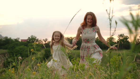 Mother And Daughter Running At The Evening Meadow