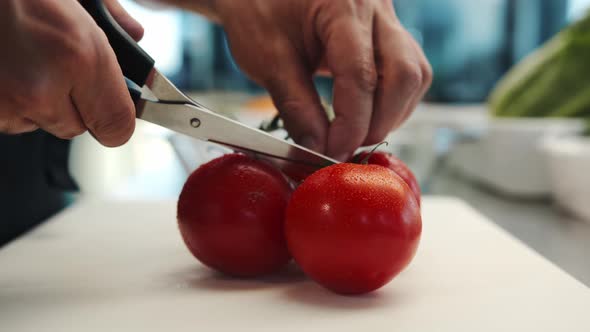 Professional restaurant kitchen, close-up: Chef cuts tomatoes with a knife