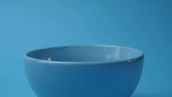 Chocolate breakfast cereals in balls are poured into a blue plate on a blue background