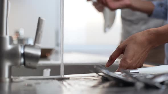 Close Up Footage of African American Female's Hands Washing Glass Dishes Under Water Jet in