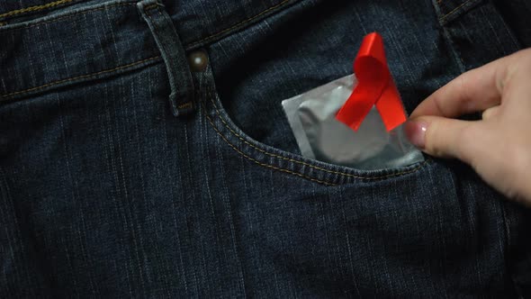 Lady Putting Condom With Red Ribbon in Jeans Pocket, Safe Sex, AIDS Prevention