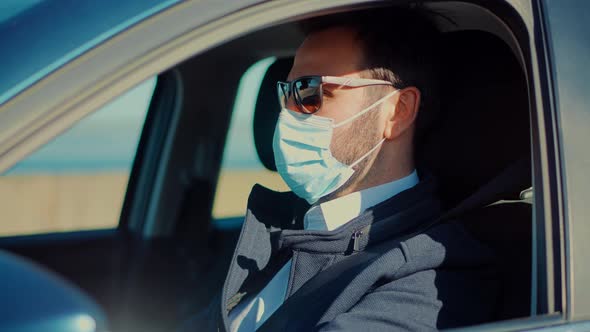 Driver Protective Face Mask In Car. Businessman In Sunglasses Drive Vehicle. Self Isolation On Car.