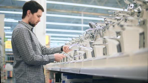 Man Choosing Faucet in the Home Improvement Store