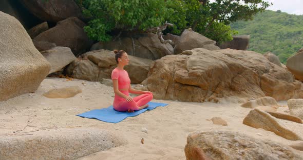 Woman Practicing Yoga in the Morning She Seats on the Beach on Yoga Mat and Meditating