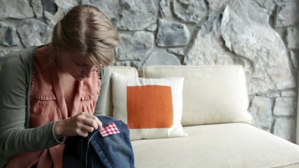 Young woman reparing clothing on sofa