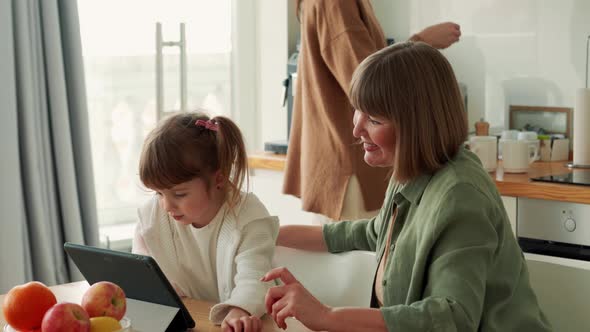 Handsome grandmother and granddaughter watching something on the tablet