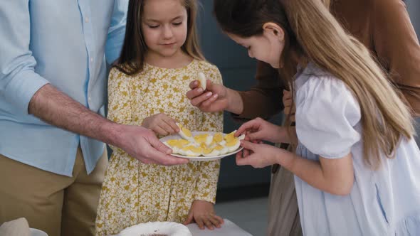 Cheerful caucasian family of four sharing with egg during easter dinner. Shot with RED helium camera