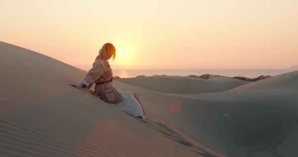 Cinematic Shot of Fashion Model Sitting on Sand Dunes Enjoying Beautiful Nature