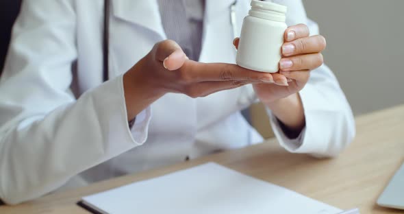 Close-up of Female Hands Passing Jar with Pills To Unrecognizable Patient. Doctor Giving Remedy To