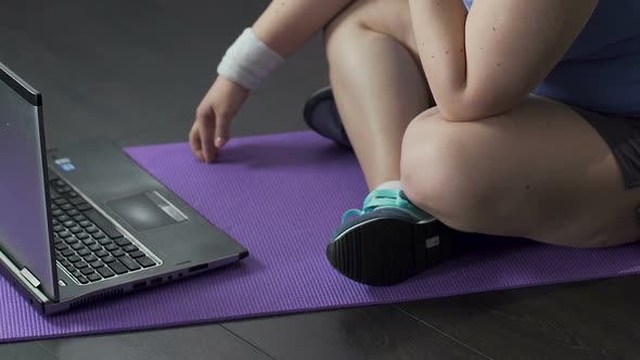 Teenager Watching Video on Laptop on Floor, Tapping Fingertips Against Yoga Mat