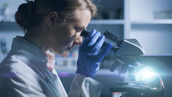 A Woman Scientist is Looking Into Microscope Biochemical Research