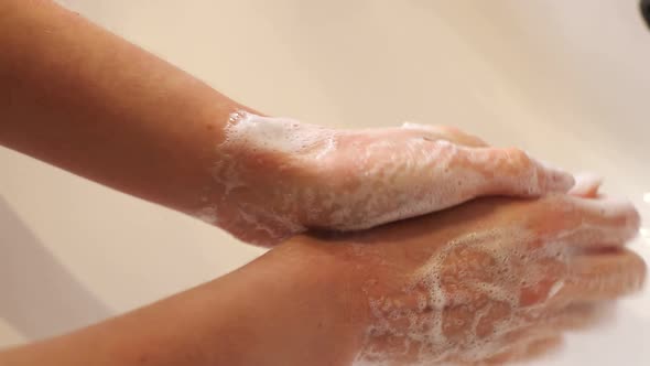 Woman Washes Her Hands in the Bathroom with Water Soap and Foam