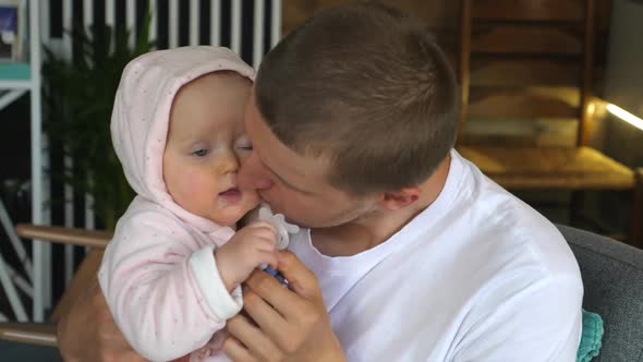 Young Father Playing and Cuddling with His Little Daughter Indoors