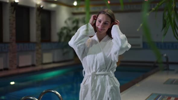 Portrait of Smiling Attractive Young Caucasian Woman in White Bathrobe Walking in Slow Motion at