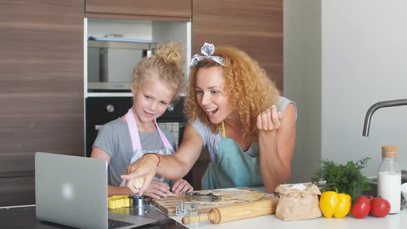 Happy Loving Mother Helps Her Daughter with Finding a New Baking Recipe