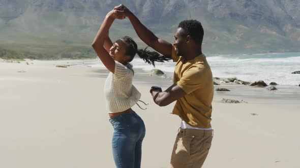 Happy african american couple dancing together at the beach