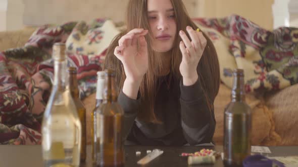 The Young Bad Looking Woman Taking Pill and Putting It Under Her Tongue Sitting on the Sofa