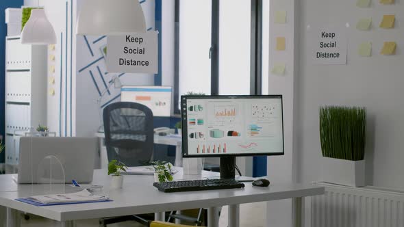 Computer with Financial Data in Modern Office Interior with Keep Social Distance Sign on the Walls