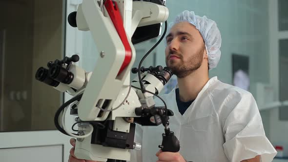 Bearded Man Loking at Monitor at Big Microscope Complex in a Hospital Laboratory