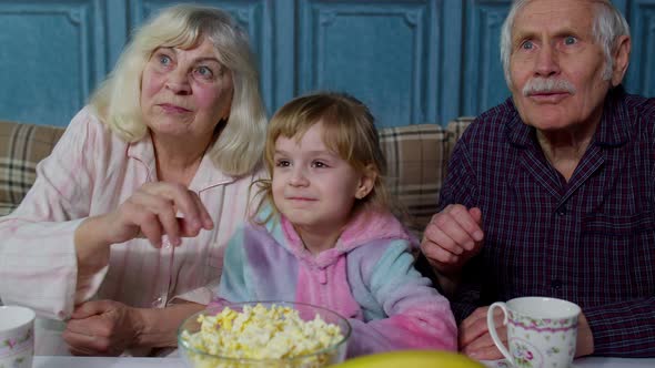 Family Grandparents Getting Scared Watching Horror TV Television Movie with Granddaughter at Home