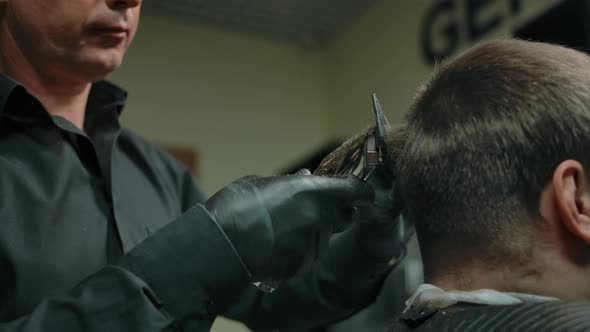 Closeup of Hairdresser Making Haircut with Trimmer to Customer