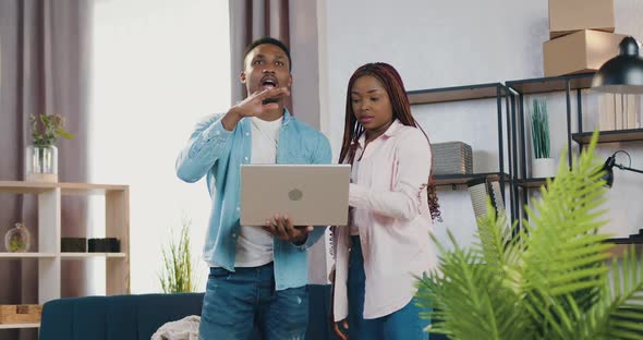 African American Couple Standing in Newly Acquired Apartment and Planning to Furnish Room